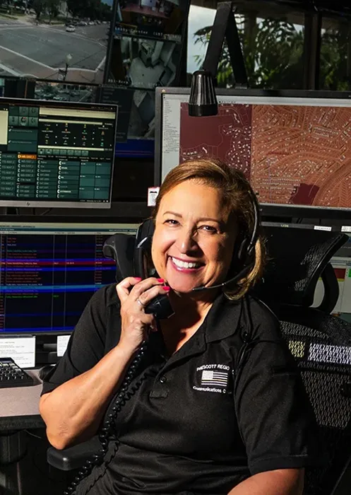 Prescott Regional dispatch lady on phone and smiling at camera.